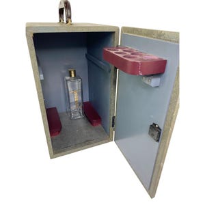 May include: A vintage wooden box with a handle, open to reveal a clear glass bottle with gold lettering and a red shelf. The interior is painted grey.