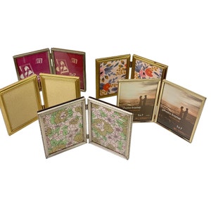 May include: Set of five gold-toned picture frames with a variety of floral and patterned designs. The frames are all 5x7 inches and have a hinged design.