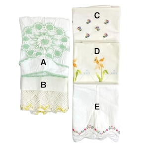 May include: Five white embroidered pillowcases with different floral designs. The pillowcases have lace trim and are labeled A, B, C, D, and E.