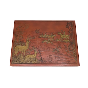 May include: A rectangular, reddish-brown box with a detailed embossed design. The design features deer, riders on horseback, and dogs in a hunting scene, with gold-colored accents. The box has a textured surface and a decorative border.