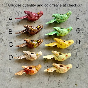 May include: Ten ceramic bird figurines in various colors and styles. The birds are all in a similar pose, with their wings outstretched and their heads tilted to the side. The birds are all about 4 inches long.
