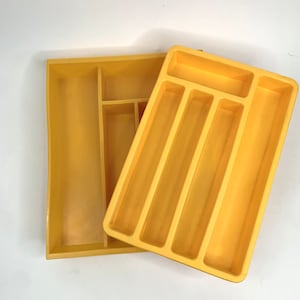 May include: A yellow plastic cutlery tray with five compartments. The tray is divided into five sections, with four long sections and one shorter section.