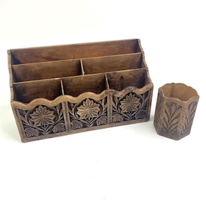Puede incluir: Un organizador de escritorio de madera con cinco compartimentos y un porta lápices a juego. Ambas piezas están intrincadamente talladas con diseños florales.