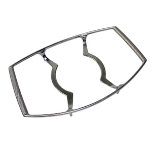 Puede incluir: Un salvamanteles de metal plateado con un marco rectangular y dos soportes curvos. Los extremos del marco tienen un diseño en espiral para agarrar. El salvamanteles está diseñado para sostener platos calientes y proteger las superficies.