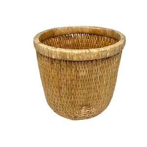 May include: A woven basket with a rounded shape and a natural, light brown color. The basket has a sturdy construction with a reinforced rim. The texture of the basket is visible, showcasing the woven pattern. This basket is suitable for storage or decoration.