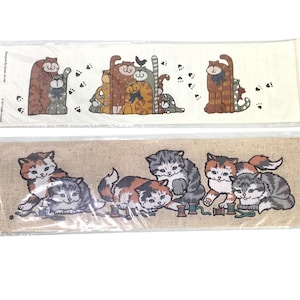May include: Two decorative fabric panels featuring cat illustrations. The top panel has a cream background with various cat designs and paw prints. The bottom panel has a tan background with kittens and spools of thread.