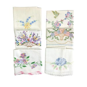 May include: Set of six embroidered white cotton pillowcases with floral and butterfly designs. The pillowcases have a lace trim.