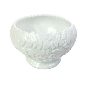 May include: White milk glass bowl with a raised leaf design. The bowl has a wide, round base and a scalloped rim.