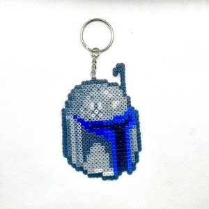 May include: A blue and gray beaded keychain shaped like a Star Wars character's helmet. The helmet has a blue visor and a gray face.