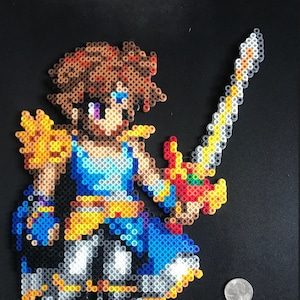 Könnte beinhalten: Eine Pixel-Art-Figur, die ein Schwert hält. Die Figur trägt ein blaues und gelbes Outfit mit braunen Haaren. Das Schwert ist silberfarben mit einem goldenen Griff.