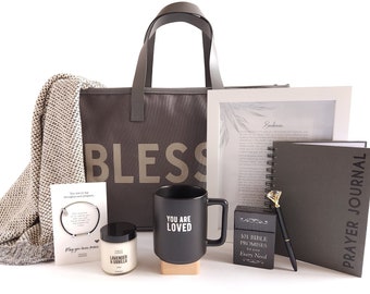 May include: A gift basket with a brown tote bag that says "Bless" on it. The basket also includes a blanket, a candle, a mug that says "You Are Loved", a prayer journal, a book of bible promises, a pen, and a bracelet.