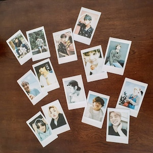 May include: A collection of 11 Polaroid-style photos featuring various individuals. The photos are arranged in a grid pattern on a wooden surface. Each photo features a different person, with some photos showing individuals smiling, while others have more serious expressions.