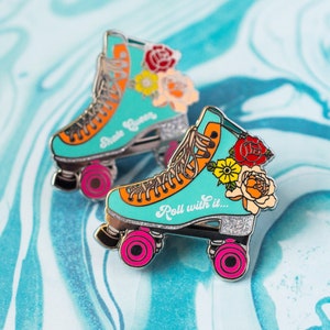Puede incluir: Dos pines de patines de ruedas turquesas con detalles naranjas, ruedas rosas y adornos florales. Un pin dice "Skate Queen", el otro dice "Roll with it..." Ambos pines tienen detalles de purpurina.