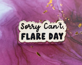 May include: White enamel pin with a gold border and black text that reads "Sorry Can't, Flare Day".