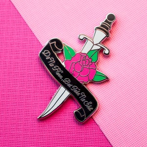 May include: Enamel pin with a dagger, pink rose, and a black banner with the text "Do No Harm, But Take No Shit." The pin has a silver outline and is set against a pink background.