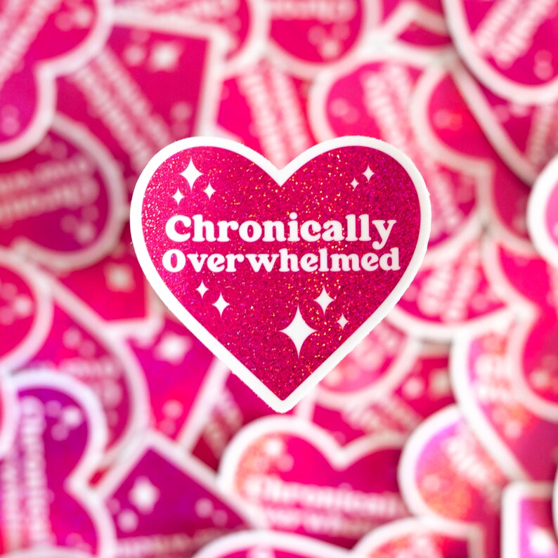 Pode incluir: Adesivo rosa em forma de cora&ccedil;&atilde;o com glitter e o texto "Cronicamente Sobrecarregado" em branco.
