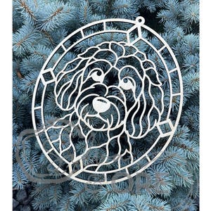 May include: A light-colored, laser-cut wooden ornament featuring a stylized, intricate portrait of a curly-haired dog breed, such as a Goldendoodle or Labradoodle, enclosed within a circular frame with geometric accents and a small hanging loop.