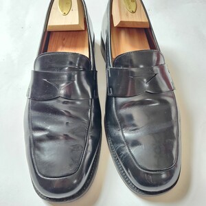 May include: A pair of black leather loafers with a simple design. The loafers have a rounded toe and a slip-on style. The shoes are on a white background.