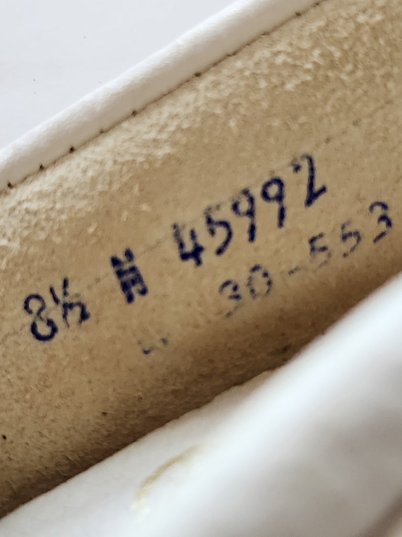 Puede incluir: Primer plano de un zapato de cuero blanco con marcas de tinta azul. Las marcas dicen "8 1/2" y "45992 30-553".