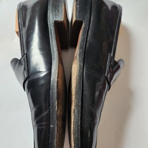 May include: A pair of black leather loafers with a polished finish. The loafers have a pointed toe and a slip-on design.