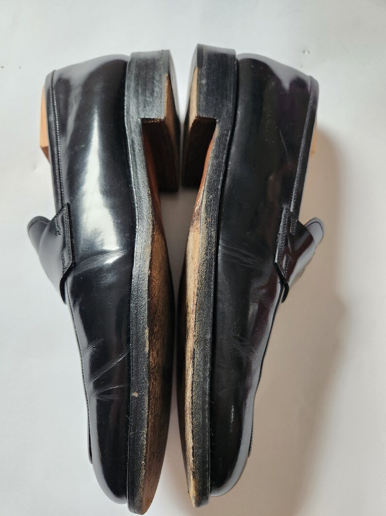 May include: A pair of black leather loafers with a polished finish. The loafers have a pointed toe and a slip-on design.