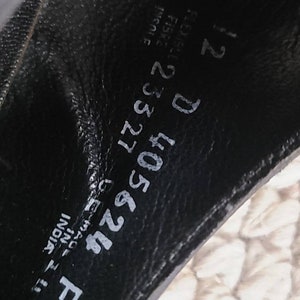 May include: Close-up of the inside of a black leather shoe. The shoe size is 12 D. The shoe is made in India. The style number is 405624.