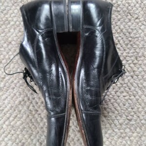 May include: A pair of black leather dress shoes with laces. The shoes have a classic design with a rounded toe and a polished finish. The soles are a dark brown color.