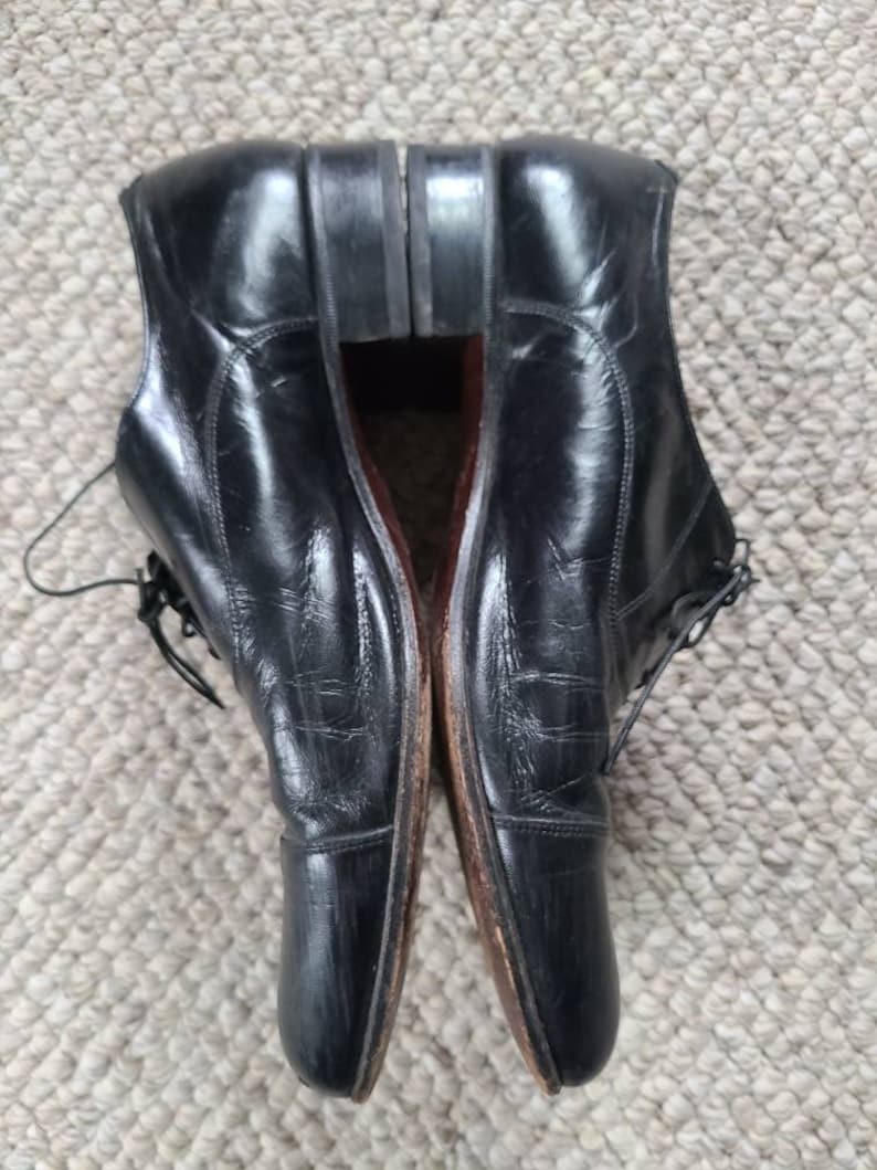May include: A pair of black leather dress shoes with laces. The shoes have a classic design with a rounded toe and a polished finish. The soles are a dark brown color.
