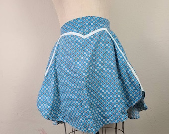 May include: A blue and white patterned skirt with a white trim. The skirt has a V-shaped waistband and a flared silhouette.
