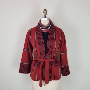 May include: A red, black, and white patterned cardigan with a tie belt. The cardigan has a geometric design and is made of a soft, knit fabric.