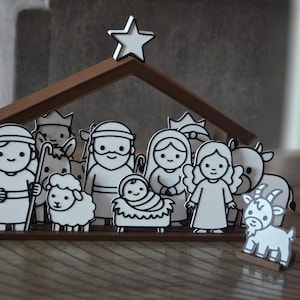 May include: A nativity scene set featuring white, cartoon-style figures with black outlines, including a baby in a manger, figures, and animals. The set is housed under a brown wooden stable structure topped with a white star.