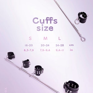 May include: A metal spreader bar with black leather cuffs featuring silver-tone buckles and rings. Text displays Cuffs size S, M, L with measurements 16-20 cm, 20-24 cm, 24-28 cm and 6.3-7.9 in, 7.9-9.4 in, 9.4-11 in. The brand name besex is visible.