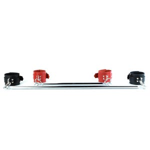 May include: A metal spreader bar featuring two black cuffs on the outer ends and two red cuffs positioned toward the center. Each cuff is secured with silver-toned metal rivets and attached to the bar using silver-toned metal rings and swivel clips.