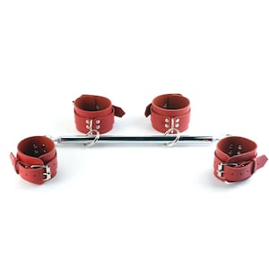 May include: A spreader bar featuring a central chrome-plated metal rod with four red adjustable cuffs attached by silver-toned metal rings. Each cuff is secured with a metal buckle and features multiple adjustment holes for a customized fit.