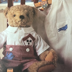 May include: A plush teddy bear wearing a white collared shirt and red gingham overalls. The shirt has a house applique and the overalls have a blue bird applique. A second white shirt with a blue bird applique is also visible.