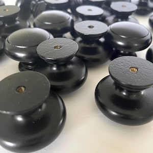 Könnte beinhalten: Eine Gruppe schwarzer, runder Holzknauf für Schränke mit einem kleinen Schraubenloch in der Mitte.