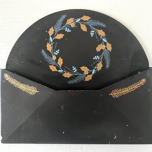 Porta cartas y correo en forma de sobre pintado de negro, con detalles pintados de acebo y pino en azul y cobre. ¡Encantador! 12,25" x 11".