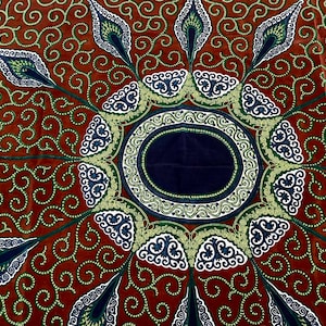 May include: A brown fabric with a circular pattern in shades of green, blue, and white. The center of the pattern is a dark blue circle surrounded by a white and gold border.