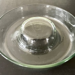 Puede incluir: Un plato de servir de vidrio transparente con un tazón central más pequeño y extraíble. El plato está diseñado para servir salsas, aperitivos o postres.