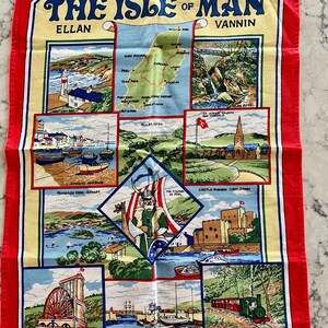 May include: A colorful tea towel with a map of the Isle of Man and illustrations of various landmarks, including the Laxey Wheel, Peel Harbour, and Castle Rushen. The text "The Isle of Man" is printed in a bold, decorative font.