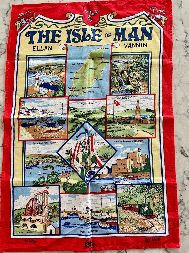 May include: A colorful tea towel with a map of the Isle of Man and illustrations of various landmarks, including the Laxey Wheel, Peel Harbour, and Castle Rushen. The text "The Isle of Man" is printed in a bold, decorative font.