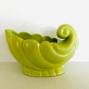 Maceta de cerámica vintage en color verde lima, con diseño de cornucopia o concha, en excelente estado; 22,2 cm de largo x 13,3 cm de ancho x 15,2 cm de alto.