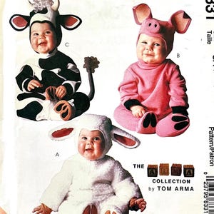May include: A sewing pattern envelope for the Tom Arma collection featuring three animal costumes for infants. The designs include a black and white cow, a pink pig, and a white lamb, each with a matching hood. The text 8331, Size, CA (1/2, 1, 2), and The Arma Collection by Tom Arma are printed on the front.