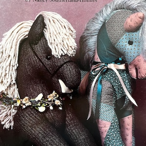May include: Two handmade stuffed horse toys. One is dark brown with a cream-colored mane and a floral wreath. The other is patchwork with blue, pink, and green fabrics, a gray mane, and ribbon accents. Both have button eyes.