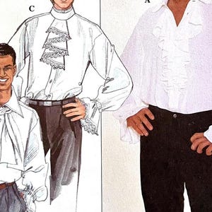 Puede incluir: Dos camisas blancas de manga larga con cuellos y puños con volantes. Una camisa tiene una corbata de lazo grande y la otra tiene un cuello con volantes más pequeño.
