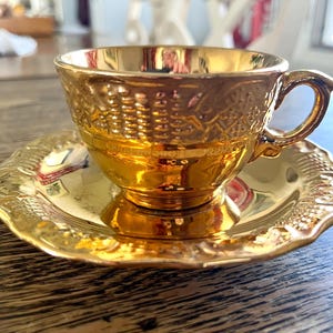 Mid-century 22 karat gold porcelain cups and saucers with texture designs, shiny gold finish, 5 sets, one extra cup, selling separately.