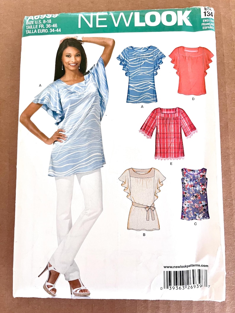 May include: A New Look sewing pattern featuring various women's top designs. The pattern includes a tunic with wave-like patterns, a red plaid top, and other styles. The model is wearing a blue tunic with white pants.