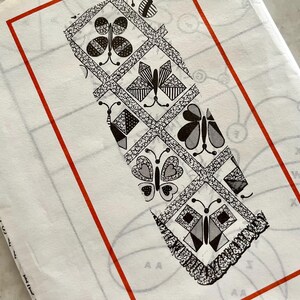 Könnte beinhalten: Ein weißer Stoff mit rotem Rand, der ein schwarz-weißes Schmetterlingsmuster aufweist. Das Design umfasst verschiedene Schmetterlingsformen in Rauten- und Quadratmustern mit einem dekorativen Rand. Der Stoff scheint gefaltet zu sein.