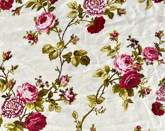 May include: White fabric with a repeating pattern of pink and red roses with green leaves.