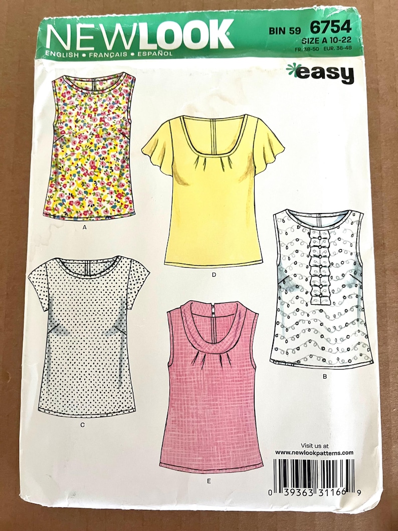 May include: A New Look sewing pattern envelope featuring illustrations of five different tops. The tops include a floral print, a yellow top with ruffled sleeves, a polka dot top, a pink top, and a white top with ruffles.